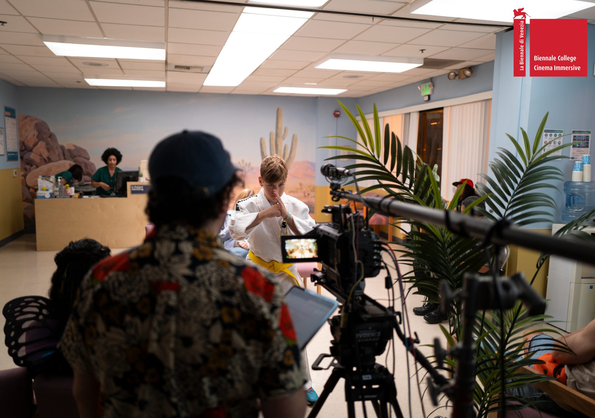 The crew filming on the waiting-room set with a camera on a tripod and a boom microphone