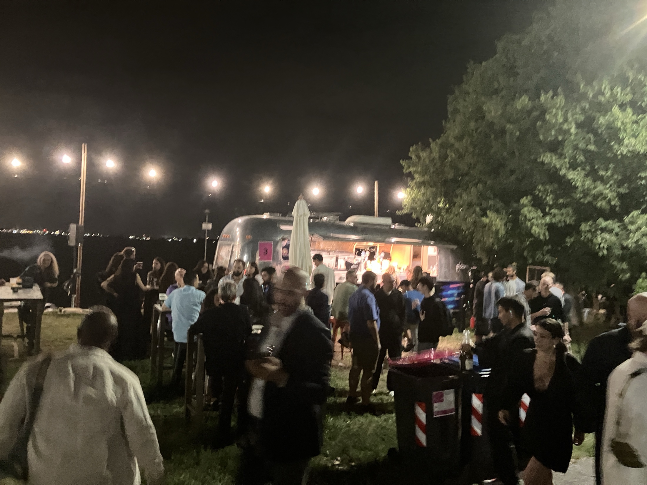 Festival attendees gathering at a waterfront bar on the Lido at night.